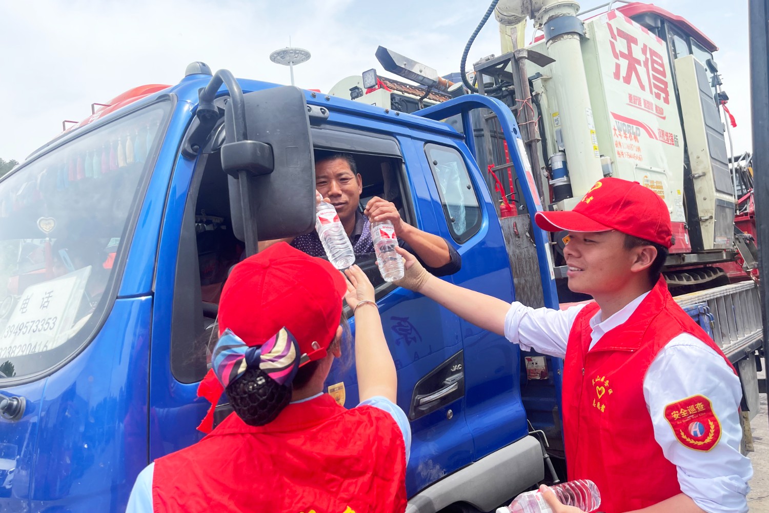 靈山服務區三夏服務志愿者為跨區域機收司乘免費送水.jpg